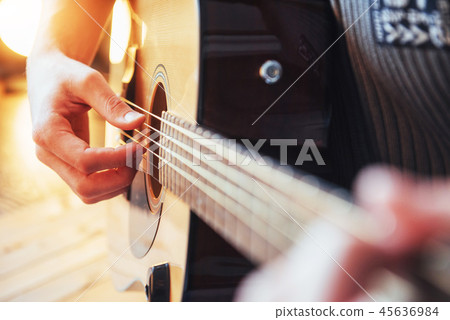 Guitarist plays guitar on wooden background, close up Guitarist plays guitar on wooden background, close up 45636984