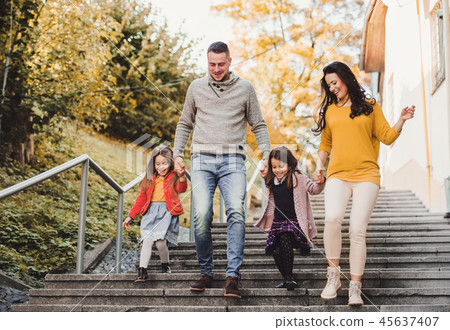 A young family with children walking down the stairs outdoors in town in autumn. 45637407