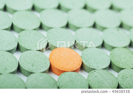 Medical green and one orange pill for the treatment and health care on a white background 45638538
