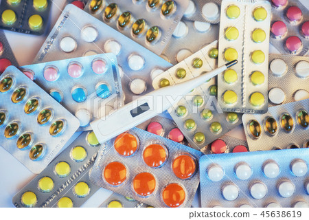 Flu. Thermometer with elevated temperature and many pills on light background 45638619