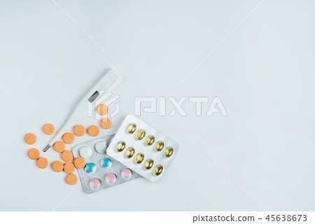 Flu. Thermometer with elevated temperature and many pills on light background 45638673