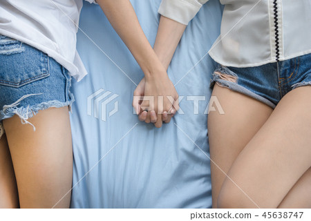 Lesbians sleeping and holding hands on bed 45638747
