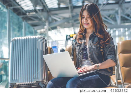 Beauty Asian woman using laptop with suitcase while waiting for Beauty Asian woman using laptop with suitcase while waiting for 45638882