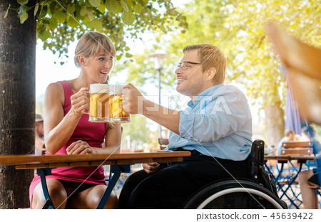 Disabled man in wheelchair and friend drinking beer 45639422