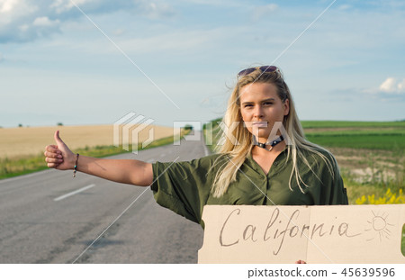 Beautiful girl hitchhiking on the road traveling. Beautiful girl hitchhiking on the road traveling. 45639596