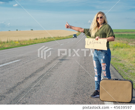 Beautiful girl hitchhiking on the road traveling. Beautiful girl hitchhiking on the road traveling. 45639597