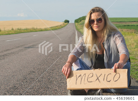 Beautiful girl hitchhiking on the road traveling. 45639601
