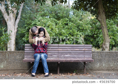 Couple hugging on a park bench 45639700