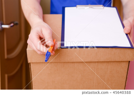 Photo close up of courier with pen, blank sheet of paper, cardboard box 45640388