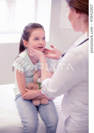 Cute girl wearing jeans sitting with her toy while visiting doctor 45642007
