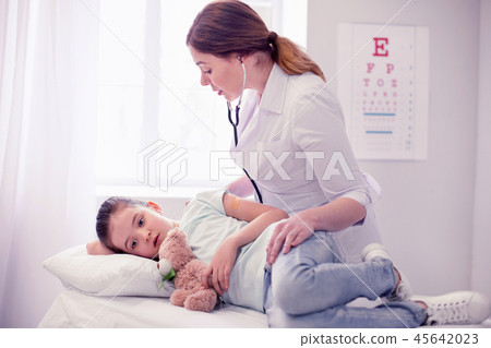 Caring dark-haired family physician coming to visit little sick girl Caring dark-haired family physician coming to visit little sick girl 45642023
