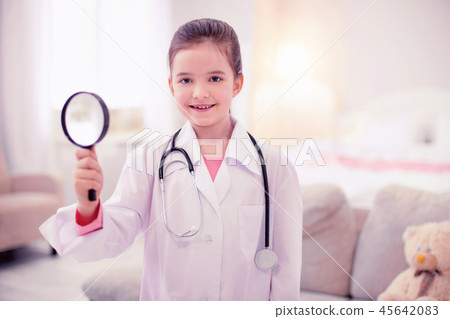 Little girl holding magnifying glass pretending to be a doctor Little girl holding magnifying glass pretending to be a doctor 45642083