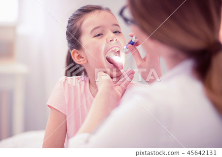 Smiling general practitioner pouring some medication for sick girl 45642131