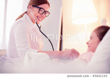 General practitioner seeing little sick girl lying in bed in positive mood General practitioner seeing little sick girl lying in bed in positive mood 45642143