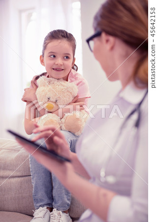Cute little dark-haired girl listening to family practitioner attentively 45642158