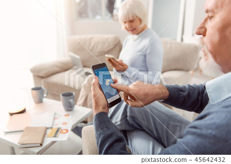Couple of pensioners playing on the smartphones Couple of pensioners playing on the smartphones 45642432