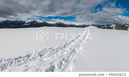 Sledge trace and footprints on winter mountain 45642633