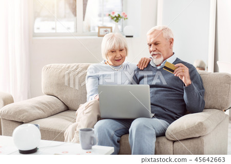 Grey-bearded man and short-haired woman making purchase online 45642663