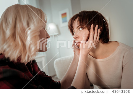 Good-looking blond woman holding her friend face 45643108