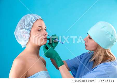 Cosmetic surgeon examining female client in office. Doctor checking woman's face, the eyelid before 45643144