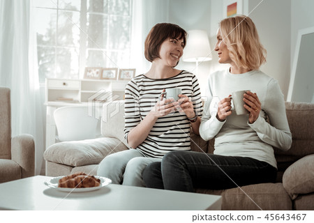 Female friends having hot drinks and croissants for breakfast Female friends having hot drinks and croissants for breakfast 45643467