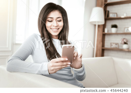 Positive delighted girl sitting in cozy sofa 45644240