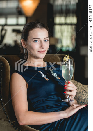 Fashionable gorgeous girl in a dark blue dress drinking cocktail in a luxery hotel lobby bar Fashionable gorgeous girl in a dark blue dress drinking cocktail in a luxery hotel lobby bar 45646585