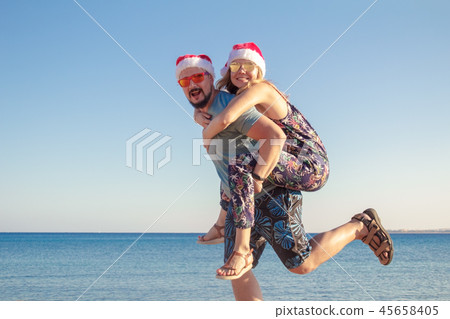 man piggybacking girlfriend in christmas hats man piggybacking girlfriend in christmas hats 45658405