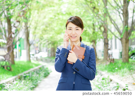 Woman making a phone call while holding a notebook Woman making a phone call while holding a notebook 45659050