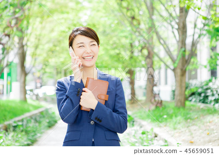 Woman making a phone call while holding a notebook Woman making a phone call while holding a notebook 45659051