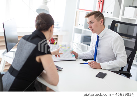 Young people sit in the office at the computer table and work with documents. Young people sit in the office at the computer table and work with documents. 45659834