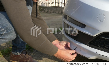 looking at a damaged vehicle. man inspects car damage after an accident 45661181