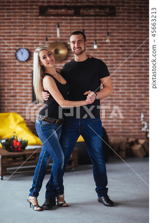 Young couple dancing latin music: Bachata, merengue, salsa. Two elegance pose on cafe with brick Young couple dancing latin music: Bachata, merengue, salsa. Two elegance pose on cafe with brick 45663213