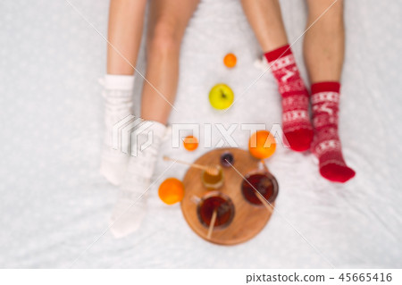 Soft photo of woman and man on the bed with tea and fruits, top view point. Female and male legs in Soft photo of woman and man on the bed with tea and fruits, top view point. Female and male legs in 45665416