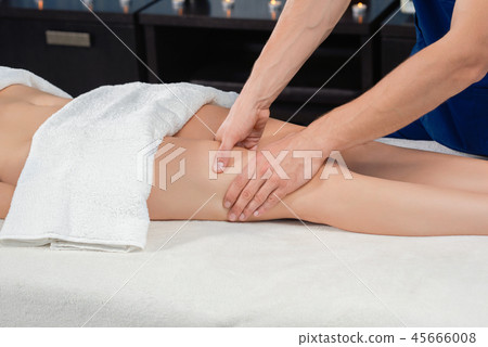 Hands of masseur massaging quadriceps of female in spa salon 45666008