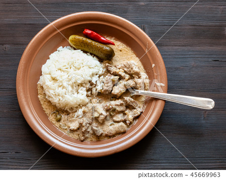 eating of Beef Stroganoff meal from brown plate 45669963