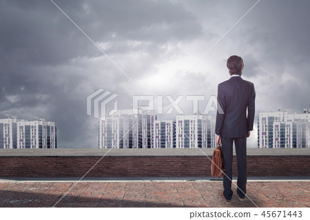 Back view of young businessman on rooftop looking at city with copy space. 45671443