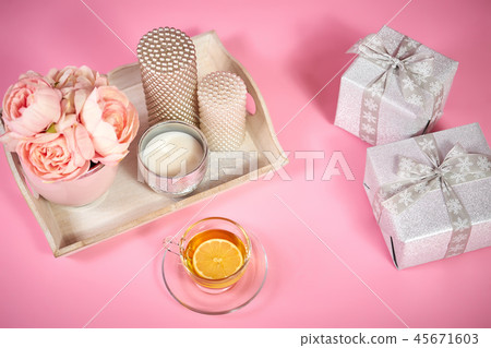 peonies, candles on a wooden tray, tea and gifts on a pink background peonies, candles on a wooden tray, tea and gifts on a pink background 45671603