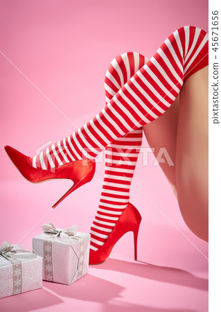 sexy santa woman's legs on a pink background and Christmas gifts 45671656