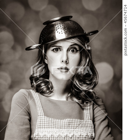 Surprised white housewife with colander on head 45674714