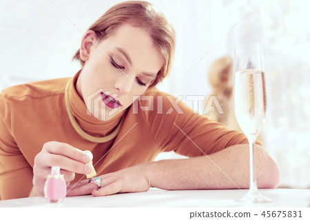 Concentrated appealing gender-queer covering his nails with polish Concentrated appealing gender-queer covering his nails with polish 45675831