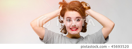Charming young girl in a gray T-shirt on a gray background. The girl holds her hands behind her head 45693520