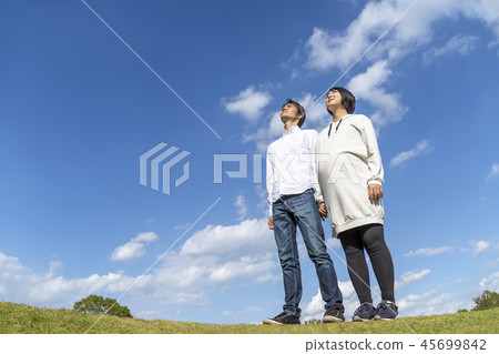 A big belly wife and husband who got pregnant against the background of the blue sky look over the distance. Pregnancy, couple, family, hope, dream, love image 45699842
