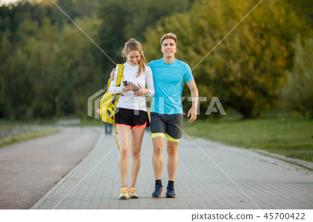 Photo of young sports women and men going in park 45700422