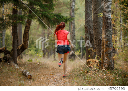 Photo from back of sports woman running through forest Photo from back of sports woman running through forest 45700593