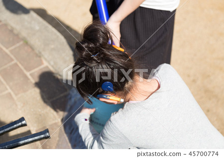 Parent and child putting air on ball in park (child with cochlear implant) 45700774