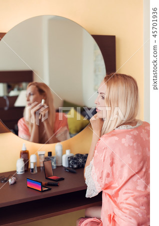 young girl in a pink silk robe sits at a boudoir 45701936