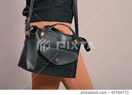 Side view of trendy woman with black hand bag hanging on her right shoulder 45704715