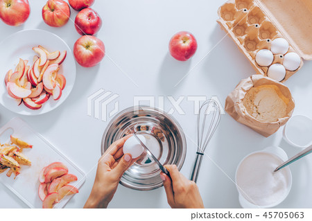 Female's hands with knife cracking egg into bowl 45705063