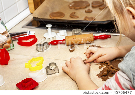 Little girl preparing a dough standing in the kitchen 45706477